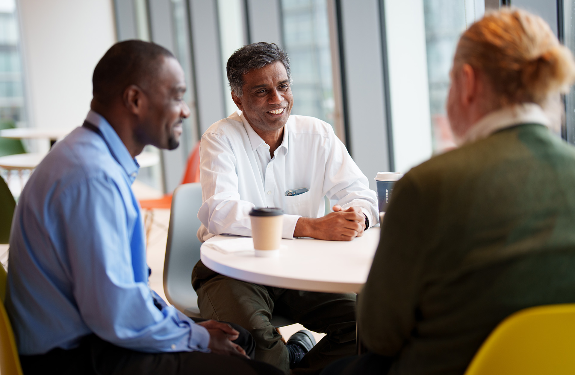 three men chatting at a table in a corporate office